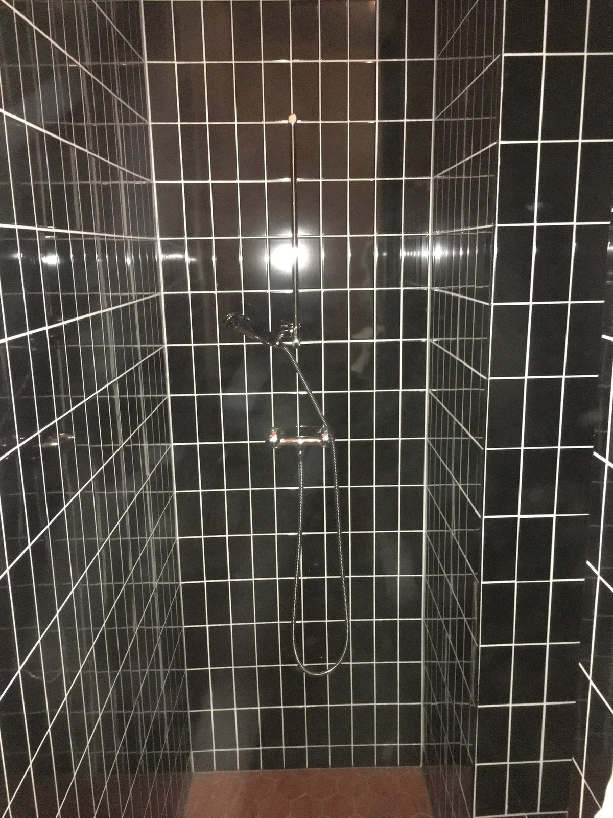 Dusche mit dunklen Platten und weissen Fugen