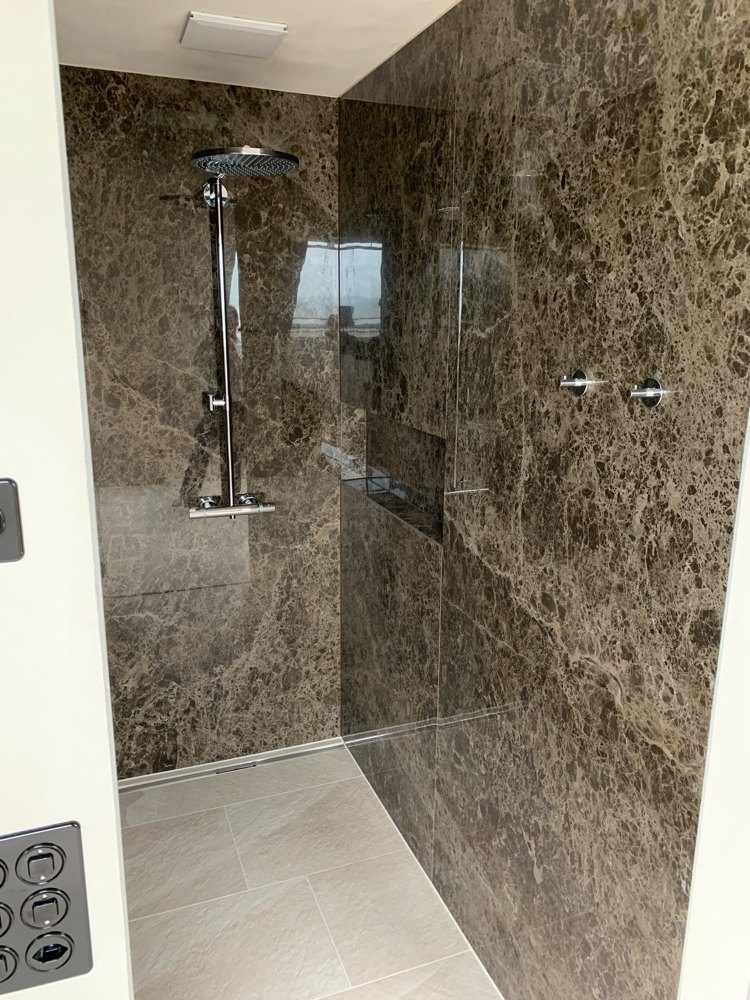 Dusche mit dunkel gemasertem Naturstein an der Wand