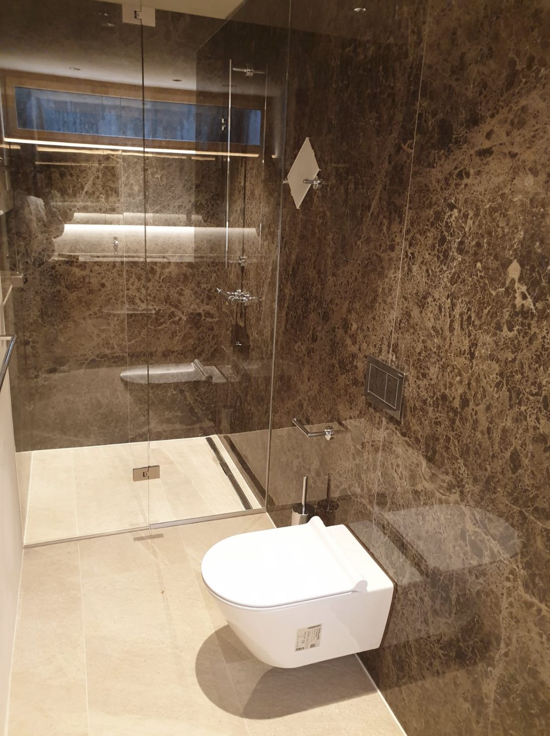 Dusche mit braun gemasertem Marmor und Natursteinboden