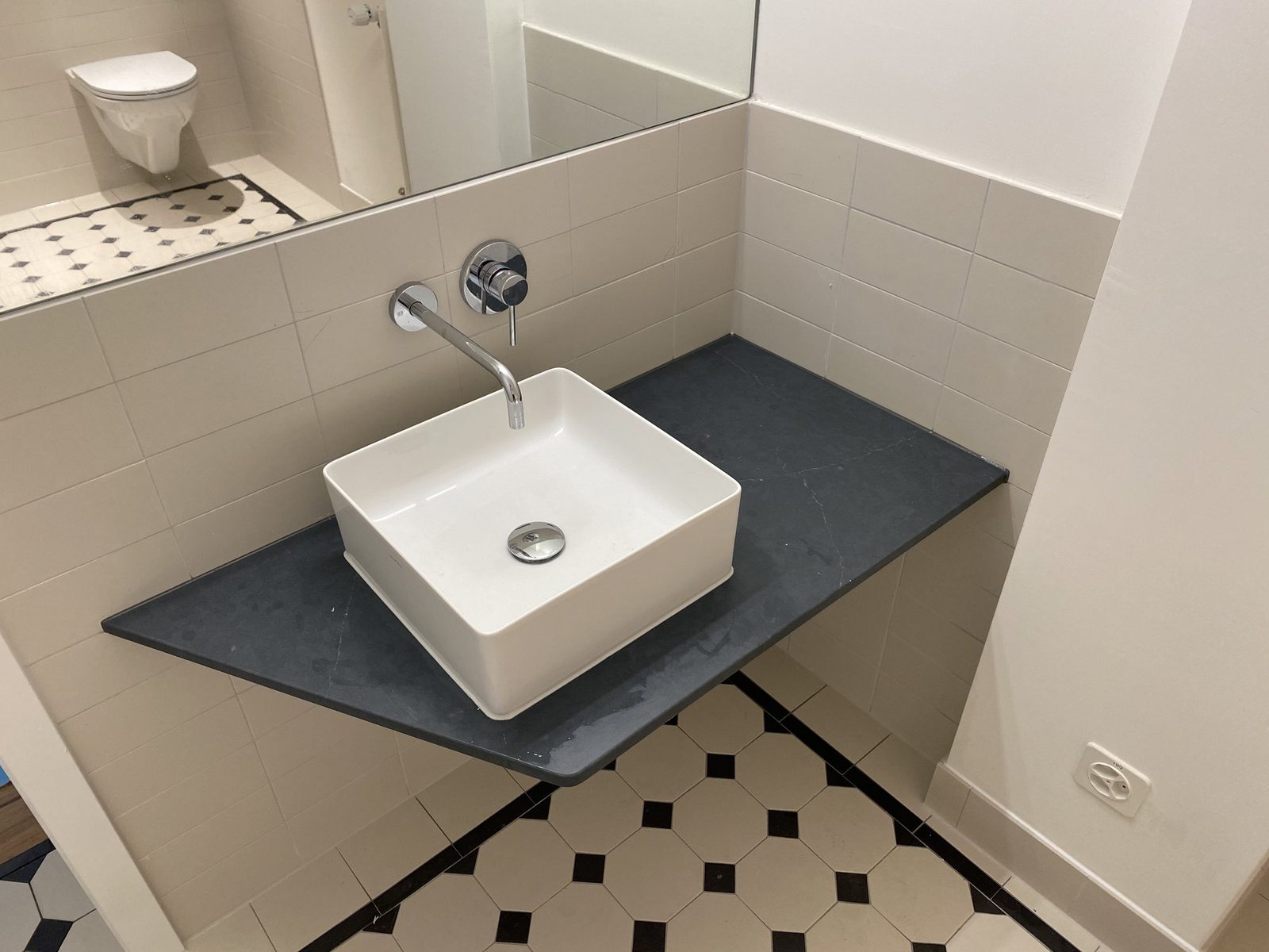 Gäste-WC mit weissem Waschbecken und schwarz-weissem Bodenbelag
