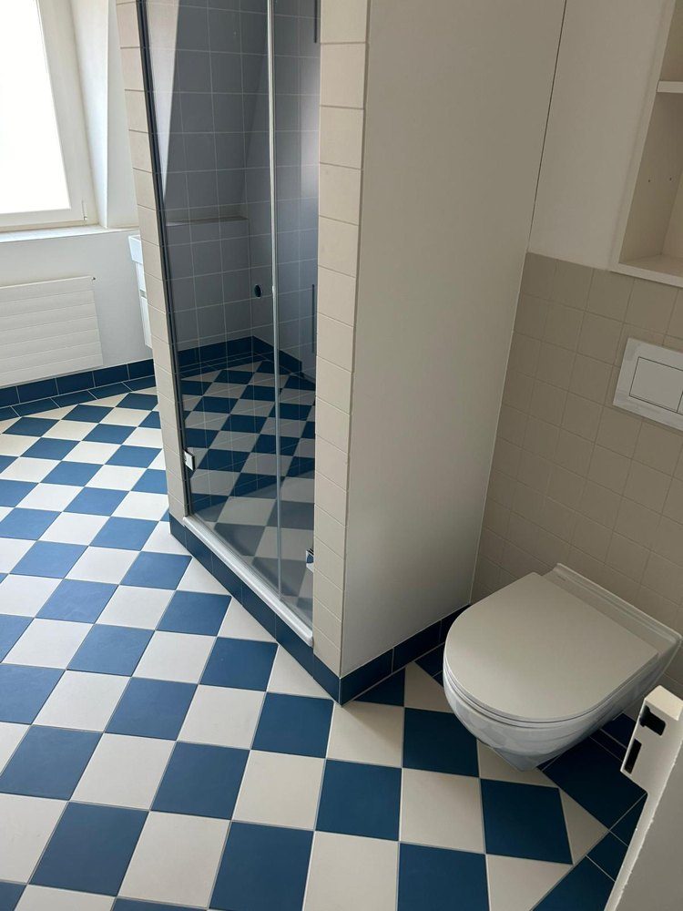 Blau-weisser Schachbrettboden in einem Badezimmer mit Duschtrennwand